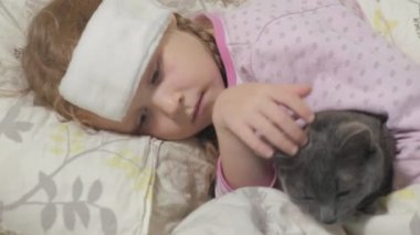 Hasta kız bir sıcaklık. Ateş bir çocukla bir kedi ile yatakta yatıyor.