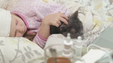 Hasta kız bir sıcaklık. Ateş bir çocukla bir kedi ile yatakta yatıyor.