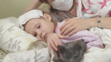 Ateşli çocuk anne ve kedi ile yatakta yalan ateşli kız hasta