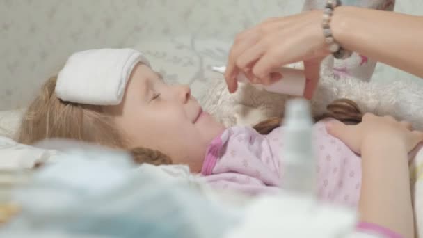 Krankes Mädchen mit Fieber. Kind mit Fieber: eine Frau, die sich um ein Kind kümmert und Medikamente nimmt — Stockvideo