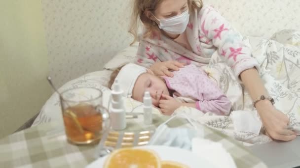 Ziek meisje met koorts kind met koorts liggend in bed met moeder — Stockvideo
