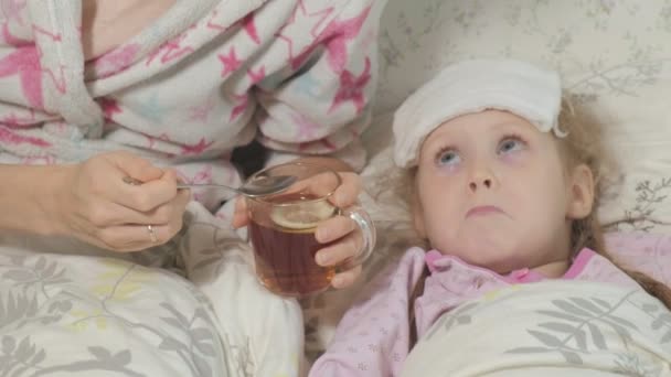 Ziek meisje met koorts. Kind met koorts: een vrouw zorg voor een kind en medicatie — Stockvideo