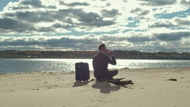 Empresário com uma mala de laptop trabalhando relaxante na praia — Vídeo de Stock