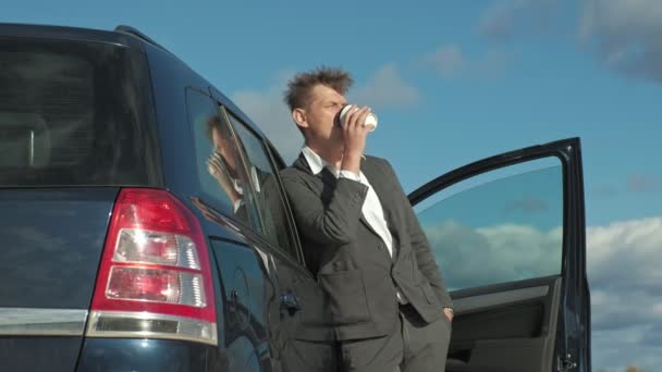 Empresario con una maleta portátil trabajando relajado en la playa cerca de su coche . — Vídeos de Stock