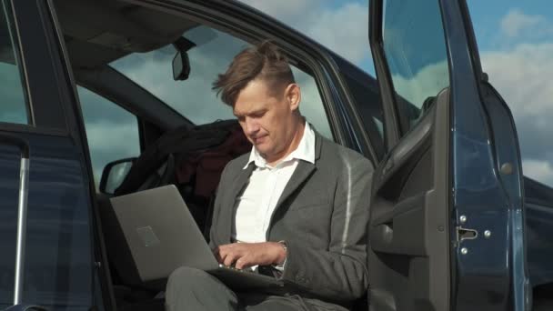 Zakenman met een koffer van de laptop werken ontspannen op het strand in de buurt van zijn auto. — Stockvideo