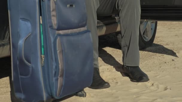 Empresario con una maleta portátil trabajando relajado en la playa cerca de su coche . — Vídeo de stock