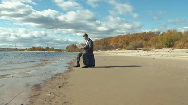 Empresario con una maleta portátil trabajando relajado en la playa — Vídeos de Stock