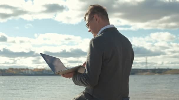 Бізнесмен з валізою для ноутбуків, що працює розслабляючись на пляжі — стокове відео