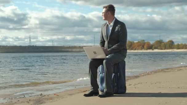 Επιχειρηματίας με μια βαλίτσα lap-top εργασίας χαλάρωση στην παραλία — Αρχείο Βίντεο