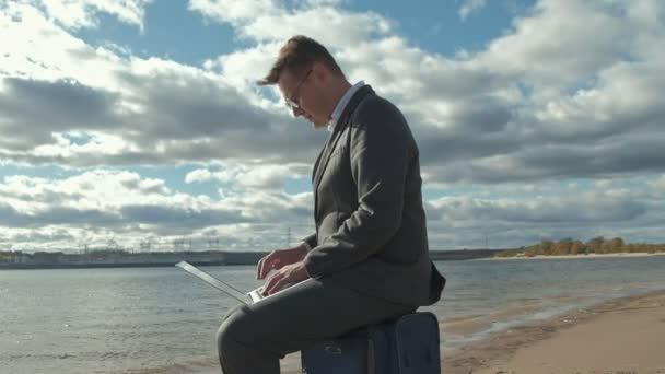 Empresário com uma mala de laptop trabalhando relaxante na praia — Vídeo de Stock