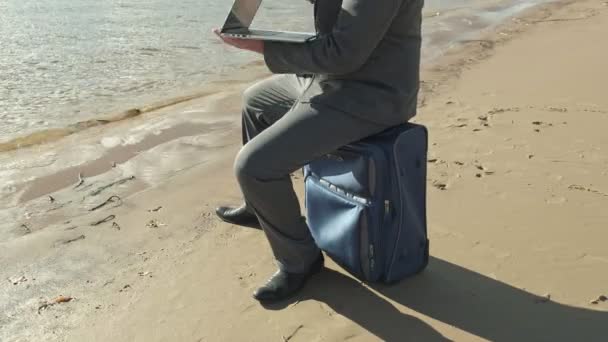 Üzletember dolgozik, pihentető a strandon, egy laptop bőrönddel — Stock videók