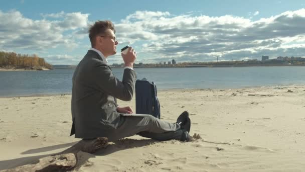 Biznesmen z walizką laptop działa, relaks na plaży — Wideo stockowe