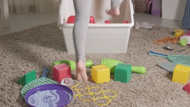 Beau petit enfant riant, blonde préscolaire, jouant avec des jouets colorés dans une boîte blanche, assis sur le sol dans la chambre — Video