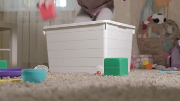 Lieblich lachendes kleines Kind, Vorschulblond, spielt mit buntem Spielzeug in einer weißen Schachtel, sitzt auf dem Boden im Zimmer — Stockvideo