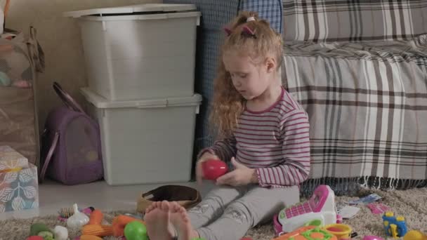 Precioso niño riendo, rubia preescolar, jugando con juguetes coloridos, sentado en el suelo en la habitación — Vídeos de Stock