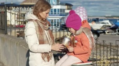 Kız, anne kızına, nehir kıyısında nehir limanı ile kadınla sandviç yeme bir içki içme