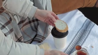 Genç kadın, sıcak giysiler, İçecek çay, nehir, nehir limanı kıyısında oturur piknik