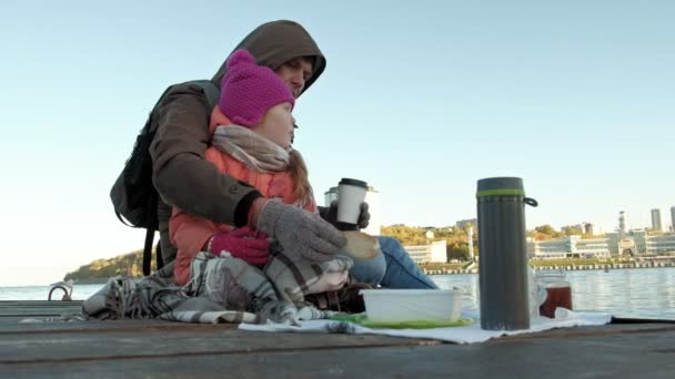 Człowiek i dziewczyna, ojciec i Córka, siedzieć w port rzeczny, pić herbatę, piknik, śmiech, w ciepłe ubrania — Wideo stockowe