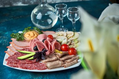 Soğuk füme et tabağı ile jambon, salam, sosis, domuz eti, peynir ve zeytin gri taş zemin üzerine.