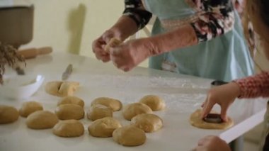 Küçük kız ve büyük annesi mutfakta dururken hamur gelen çerezleri yapmak