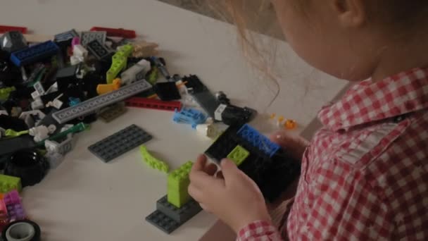 Маленькая девочка строит из дизайнерских кубиков. Радость игр — стоковое видео