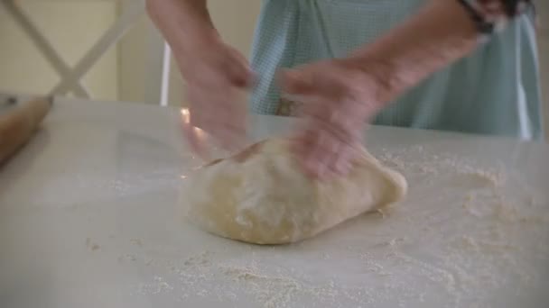 Счастливая пожилая женщина катит тесто для пиццы дома на кухне — стоковое видео