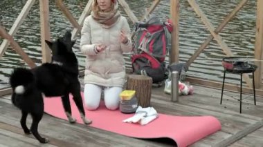 Bir kadın turist nehir kıyısında yakın köprü üzerinde oturur, açık havada yaz dağ ve deniz doğa köpek, aşçılar yemek, piknik, aktif dinlenme ve sağlıklı yaşam tarzı beslemek. Güzel ilham verici