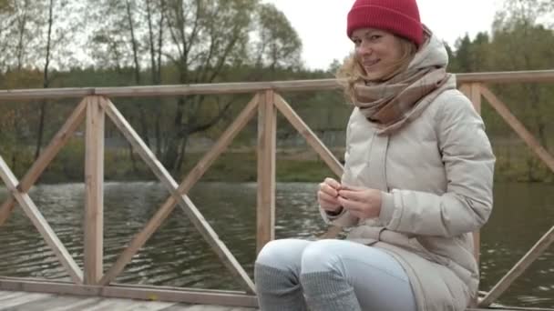 Женщина-туристка сидит на мосту у реки, кормит собаку. активный отдых на свежем воздухе и здоровый образ жизни летом в горах и морской природе. Прекрасный вдохновляющий пейзаж — стоковое видео