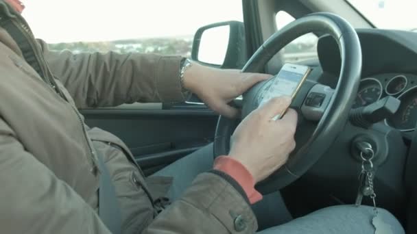Homme i assis dans la voiture et tenant téléphone portable noir avec carte GPS navigation, tonique au coucher du soleil . — Video