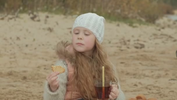 Pequeña chica pelirroja hermosa bebe té junto al mar — Vídeo de stock