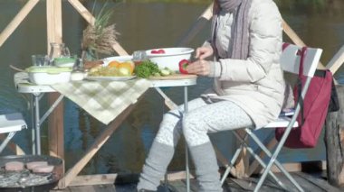 Genç kadın sıcak giysiler, piknik nehrin üzerinde bir ahşap köprü, kesme sebze, hafta sonları, soğuk hava, açık rekreasyon, Turizm tarafından