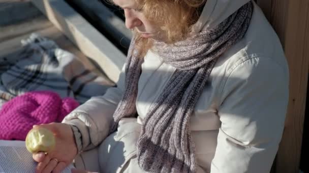 Donna sul ponte vicino al fiume autunno legge un libro e mangia una mela — Video Stock