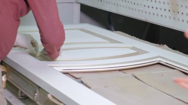 Hombre, trabajador quita cinta adhesiva protectora. producción de puertas interiores de madera — Vídeos de Stock