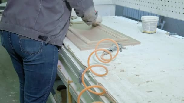 Eine Frau, eine Arbeiterin, spuckte die Türoberfläche aus. Herstellung von Innentüren aus Holz — Stockvideo