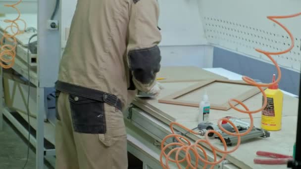 Trabajador masculino pegando espacios en blanco de madera para una puerta. producción de puertas interiores de madera — Vídeo de stock