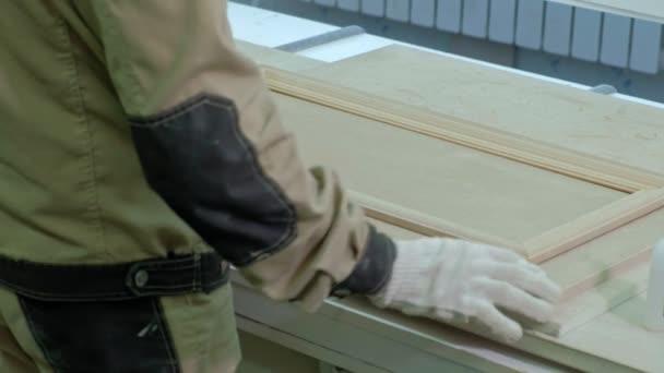 Чоловік працівник склеює дерев'яні заготовки для дверей. виробництво міжкімнатних дверей з дерева — стокове відео
