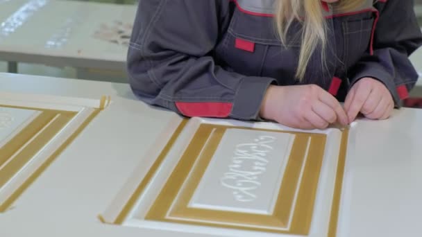 Una mujer en un taller pega una cinta protectora en la producción de puertas interiores de madera — Vídeos de Stock