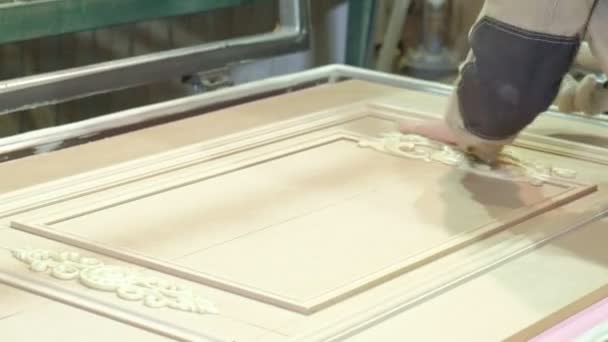 Ein Mann, ein Arbeiter reinigt einen Holzrohling vom Staub, eine Tür. Produktion von Innentüren aus Holz — Stockvideo