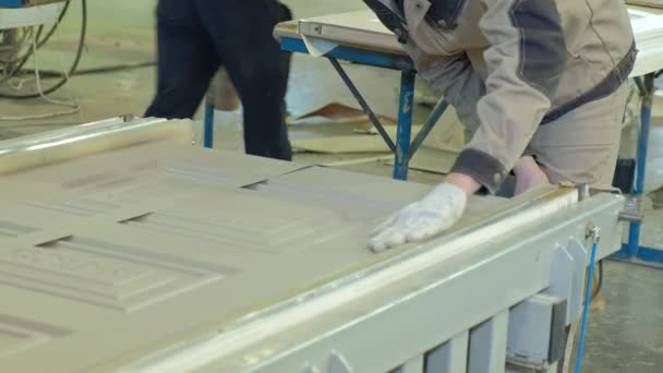 Un hombre, un trabajador limpia un blanco de madera del polvo, una puerta.producción de puertas interiores de madera — Vídeos de Stock