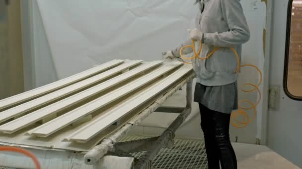 Una mujer, un trabajador, pinta un espacio en blanco de madera para hacer una puerta. El proceso de fabricación de puertas de madera. producción de puertas interiores de madera — Vídeos de Stock