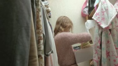 Güzel kız gülümseyerek ve onun soyunma room.close giysiler seçmek