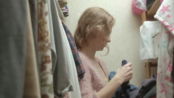 Девочка улыбается и выбирает одежду в гримерке. — стоковое видео