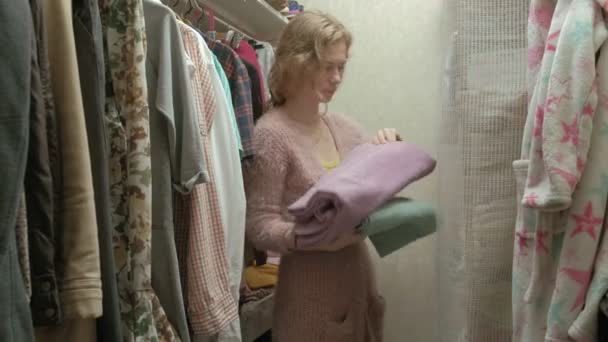 Hermosa chica sonríe y va sobre toallas en el estante en su vestidor — Vídeos de Stock