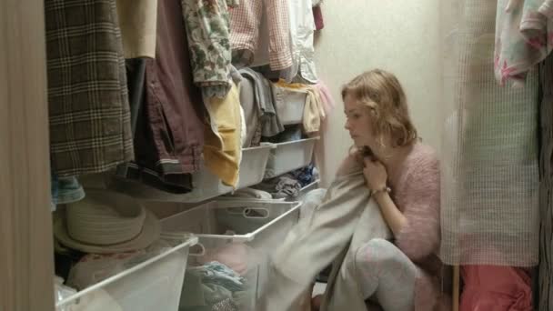 Μια όμορφη κοπέλα χαμογελάει και περνά μέσα από τα ρούχα στα συρτάρια στο καμαρίνι της. βάζει τα πράγματα στη σειρά — Αρχείο Βίντεο