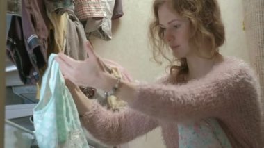 Güzel bir kız gülümsüyor, sıralar ve giysileri içinde sepetleri soyunma odasina kıvrımlar. amacıyla bir şeyler koyar