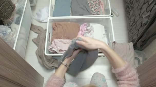 A beautiful girl goes through and folds her clothes in baskets in her dressing room. brings order. view from above — Stock Video