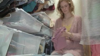 Güzel bir kız gülümsüyor, sıralar ve giysileri içinde sepetleri soyunma odasina kıvrımlar. amacıyla bir şeyler koyar