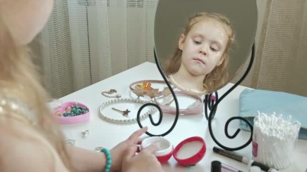 Kleines Mädchen mit roten Haaren schmiert Creme, schaut in den Spiegel, Make-up, Gesichtsbehandlung, Mode, Stil, Kosmetik, Spiegelung im Spiegel — Stockvideo