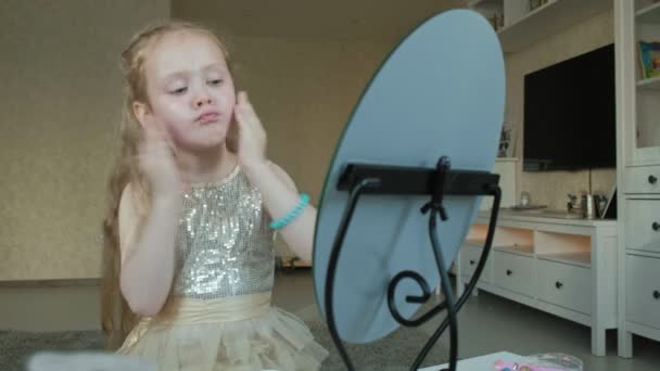 Liten flicka med rött hår utstryk grädde, ser i spegeln, makeup, ansiktsbehandling, mode, stil, kosmetika — Stockvideo