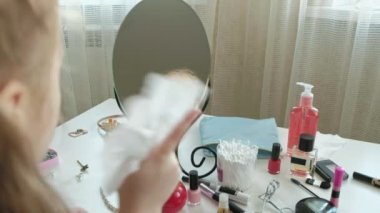 Kızıl saçlı küçük kız aynaya baktığında, ıslak mendil, kalıcı makyaj, yüz, moda, stil, kozmetik ile yüz cildi temizler